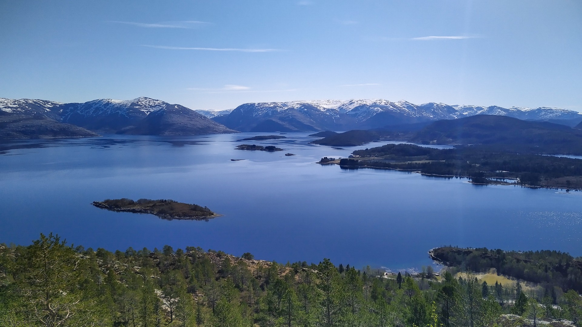 Kristallklart fjellvann med snøkronet fjellkjede i bakgrunnen
