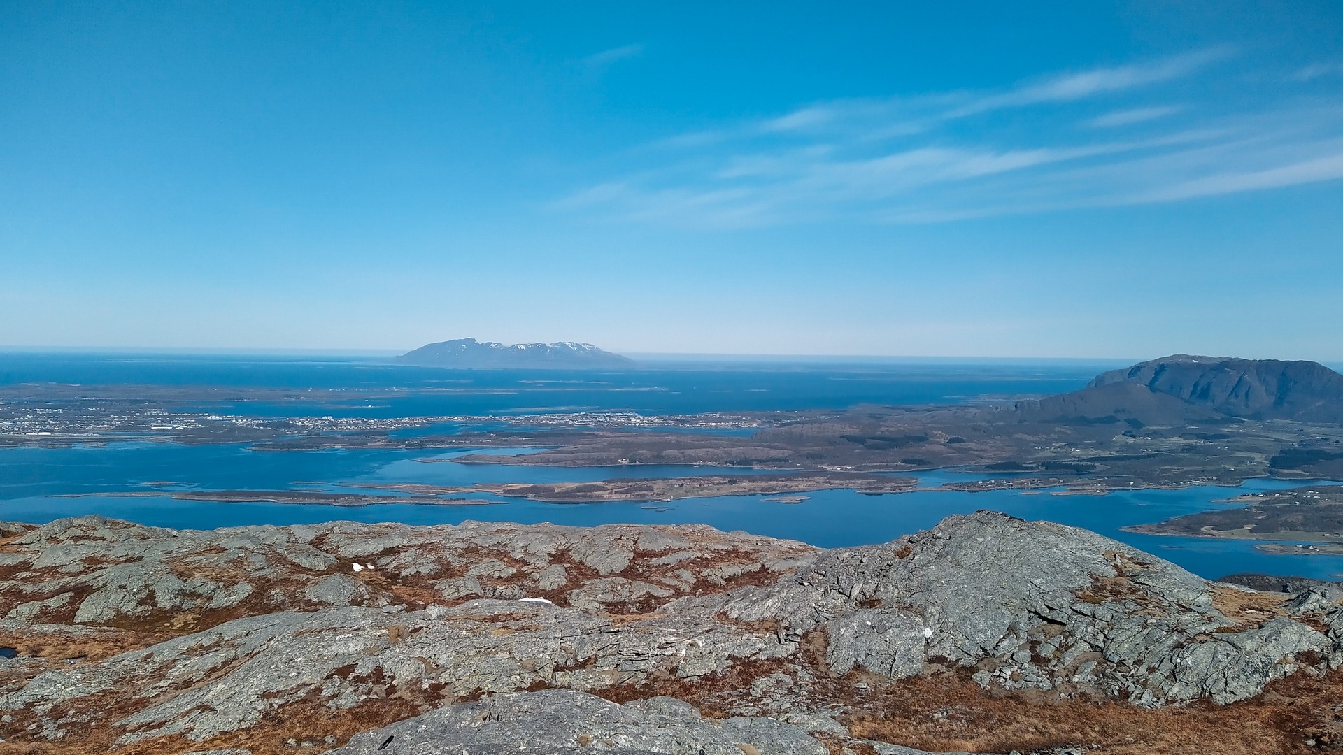Fjelltopp med utsikt over turkis sjø og snøkledt fjell